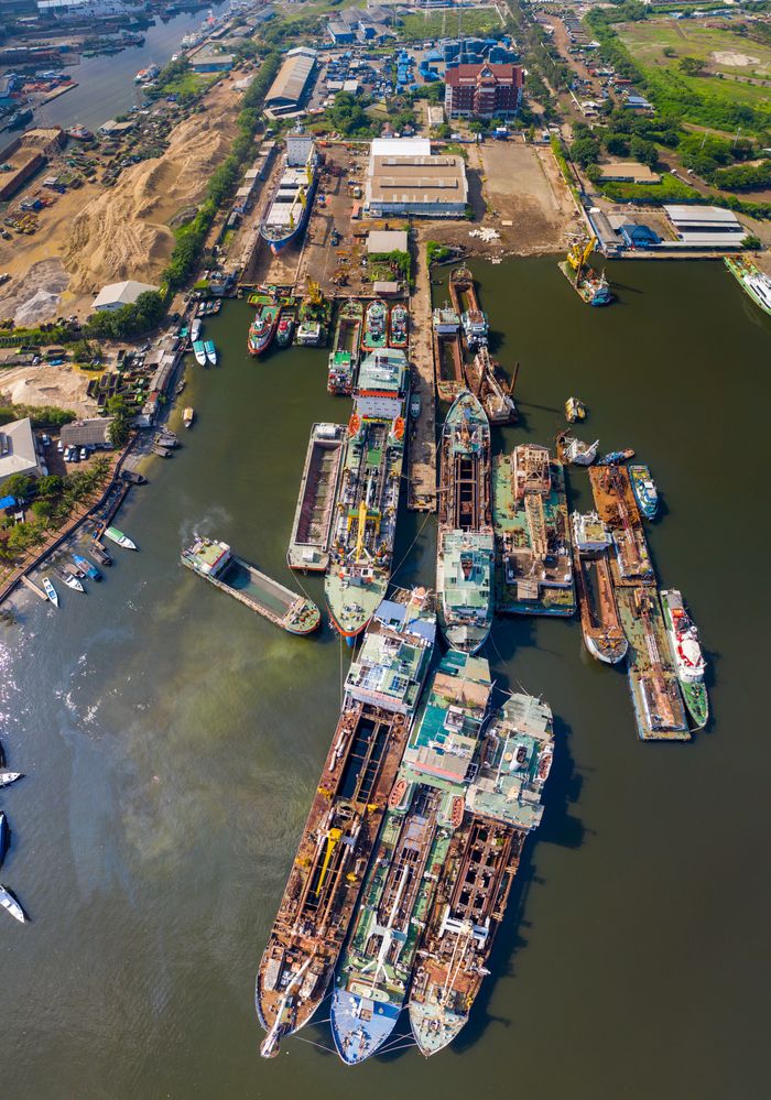 Mastering the First Impression: Your intriguing post title goes here Aerial shot of a busy shipyard in Indonesia with multiple ships docked for repair.