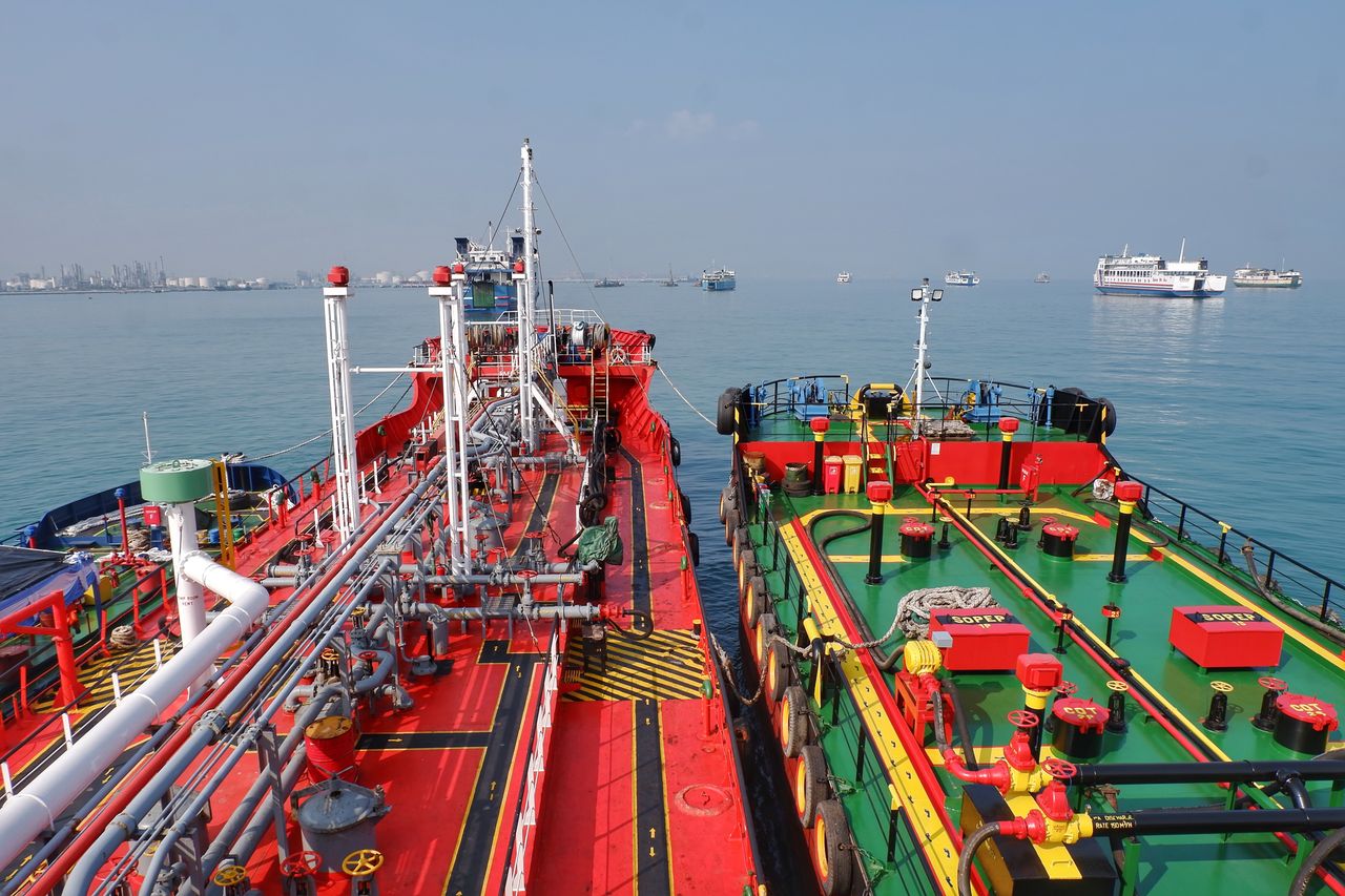 Mastering the First Impression: Your intriguing post title goes here Colorful cargo vessels docked in calm waters in Banten, Indonesia with city skyline in distance.