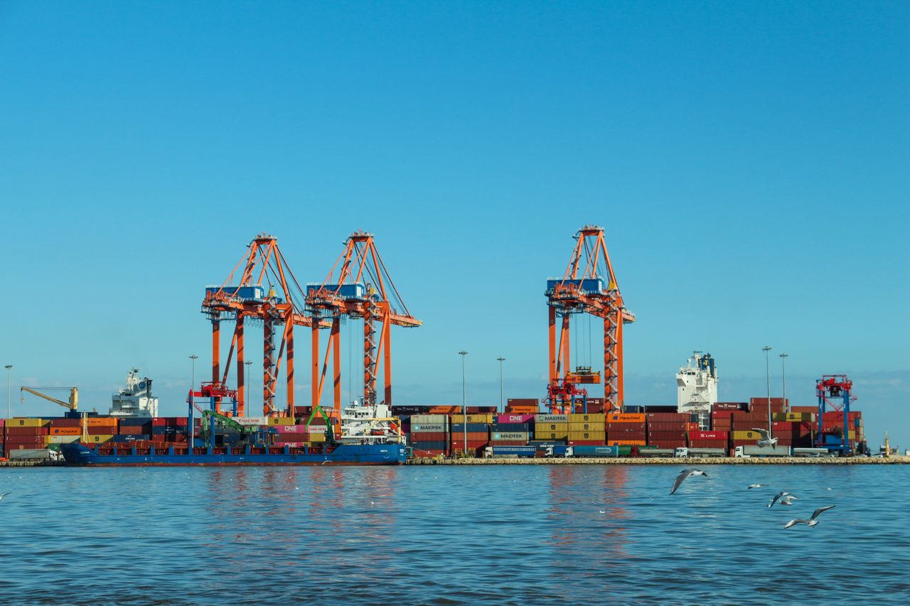 Mastering the First Impression: Your intriguing post title goes here Colorful container port with large cranes and ships against a clear blue sky.