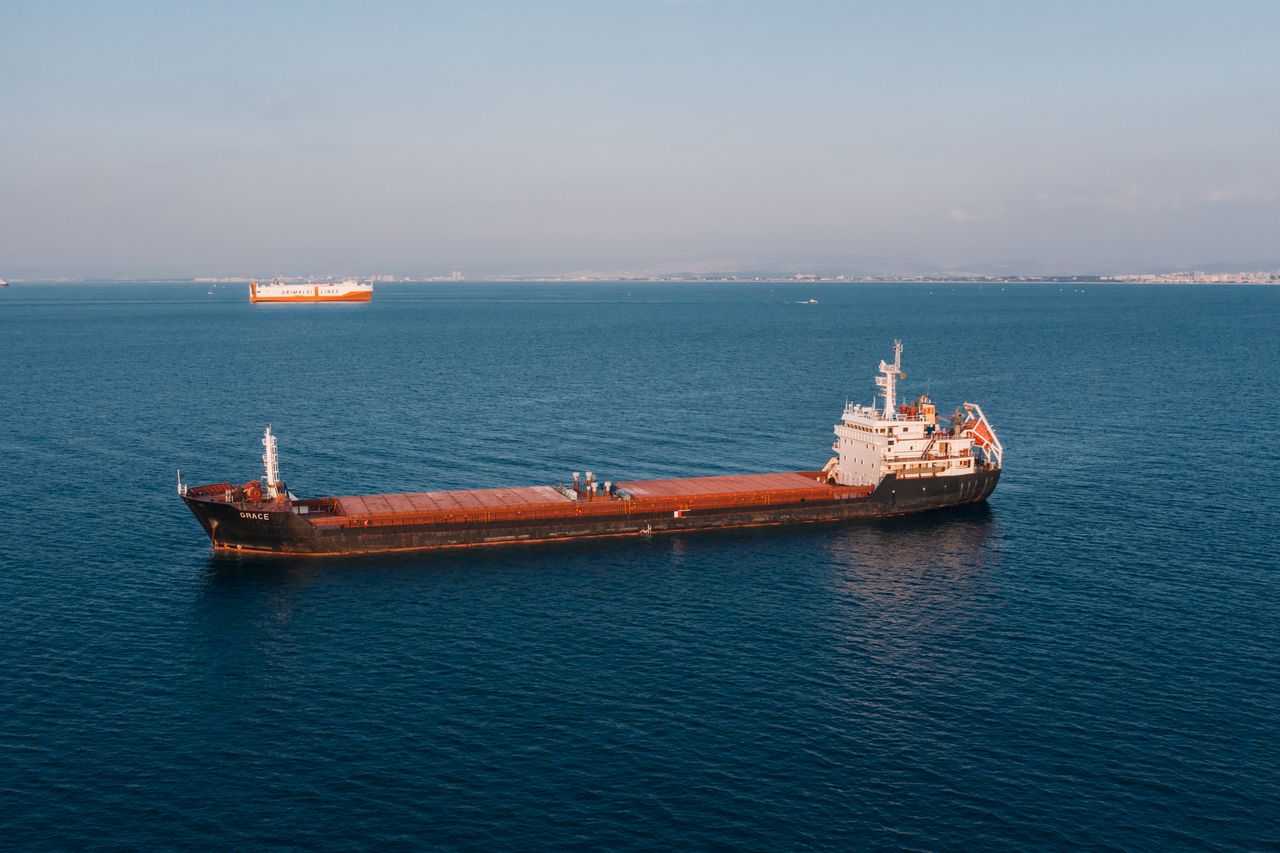 The Art of Drawing Readers In: Your attractive post title goes here Aerial view of a cargo ship sailing in the open sea under clear skies, showcasing maritime transport.
