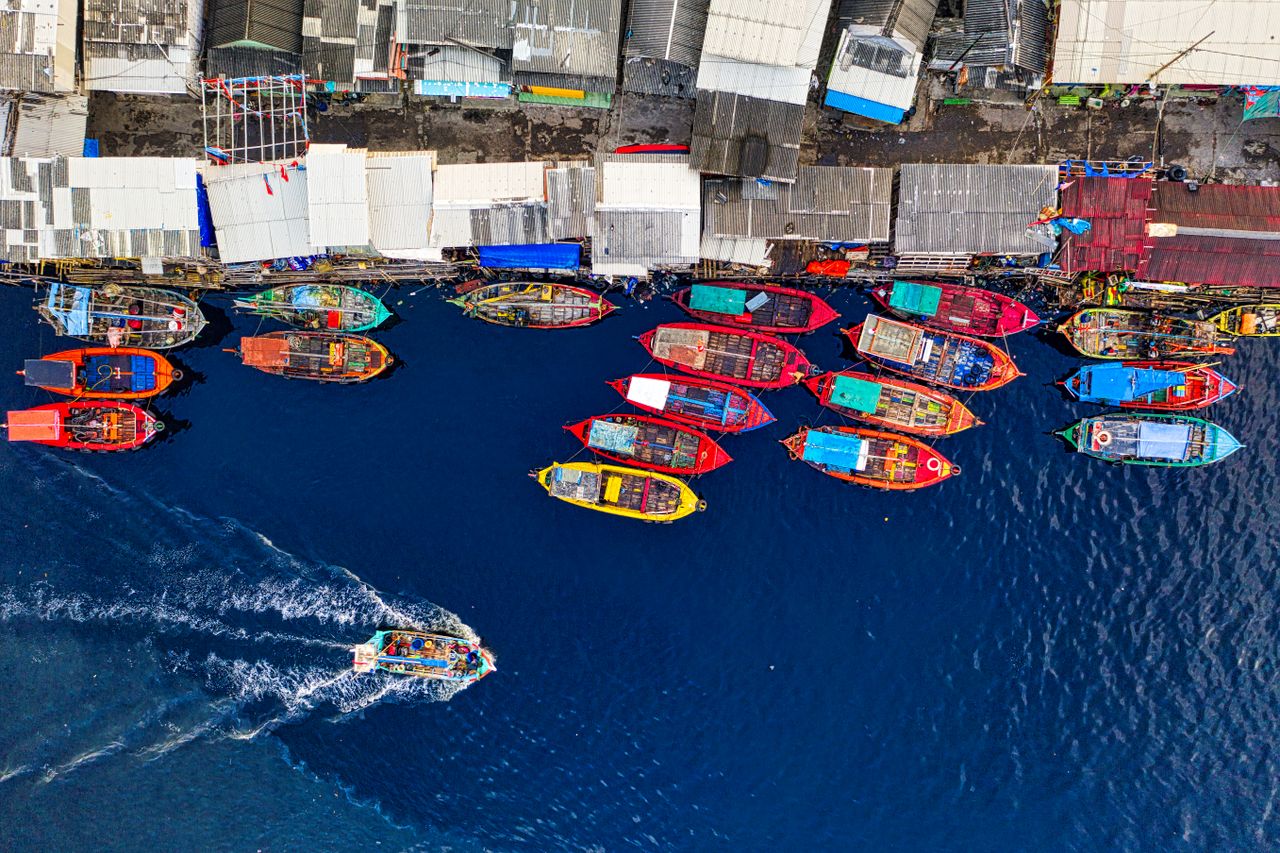 Crafting Captivating Headlines: Your awesome post title goes here Vibrant fishing boats docked at Jakarta's harbor, showcasing a bustling marine scene from above.